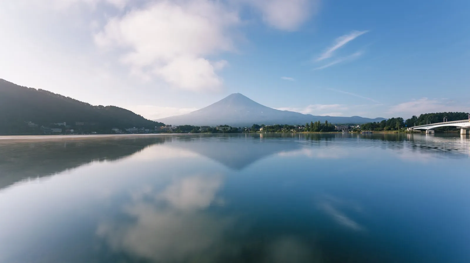 Mt Fuji and the lake bridge reflected in still water on a clear morning