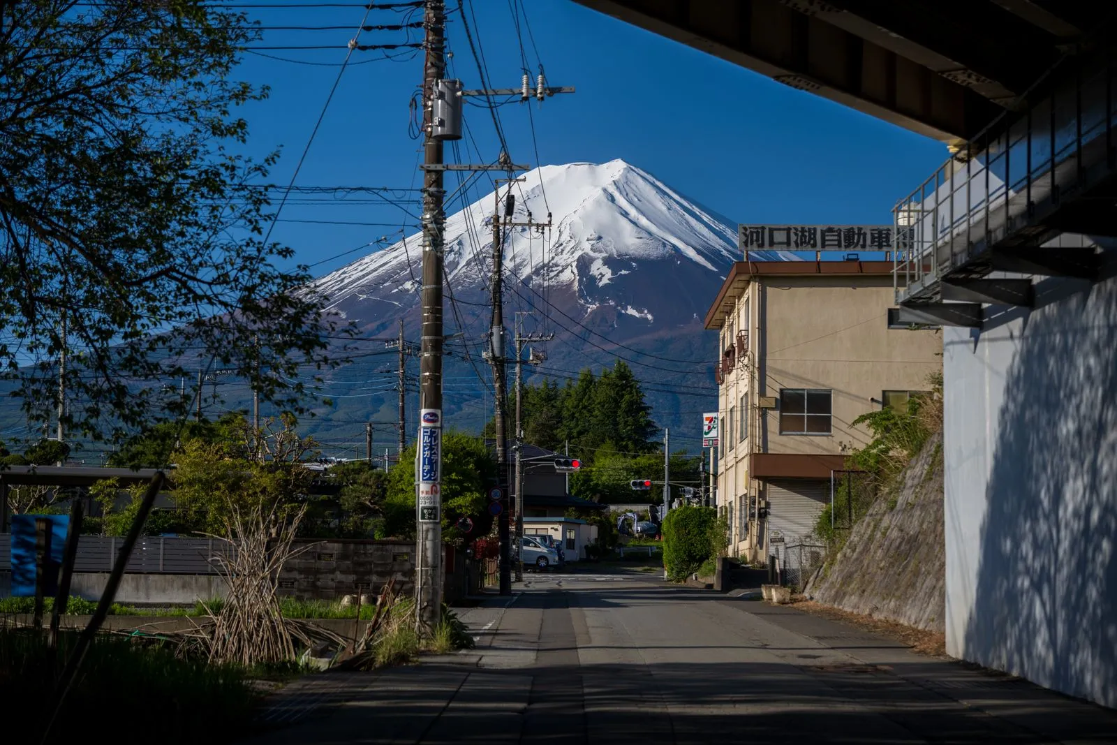 Town street lined with power lines leading toward snow-capped Mt Fuji