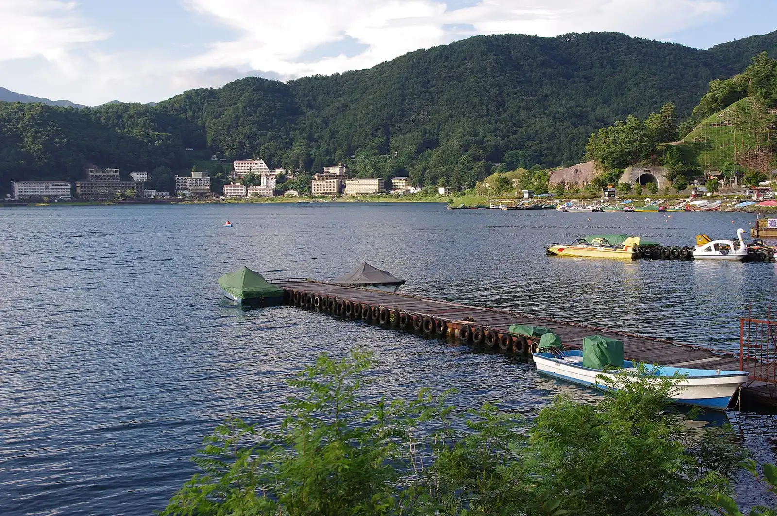 Wooden jetty with boats on Lake Kawaguchi, lakeside hotels beyond