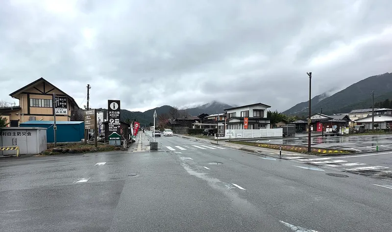 Rainy crossroads in Oishi with signs for the park, mountains in cloud