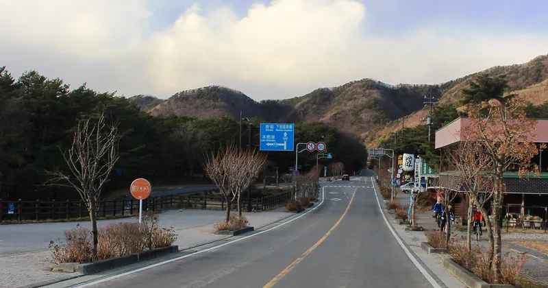 Empty road between bare winter hills, signposted for Lake Motosu