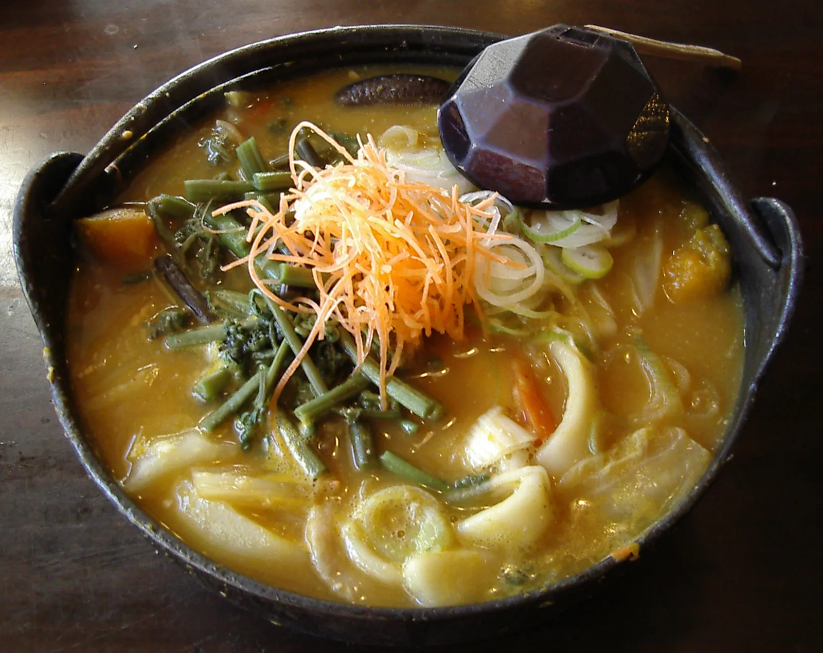 Hoto: thick flat noodles with pumpkin and mountain vegetables in miso broth, in an iron pot