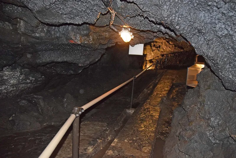 Lit walkway with a handrail through the lava tube of Fugaku Wind Cave